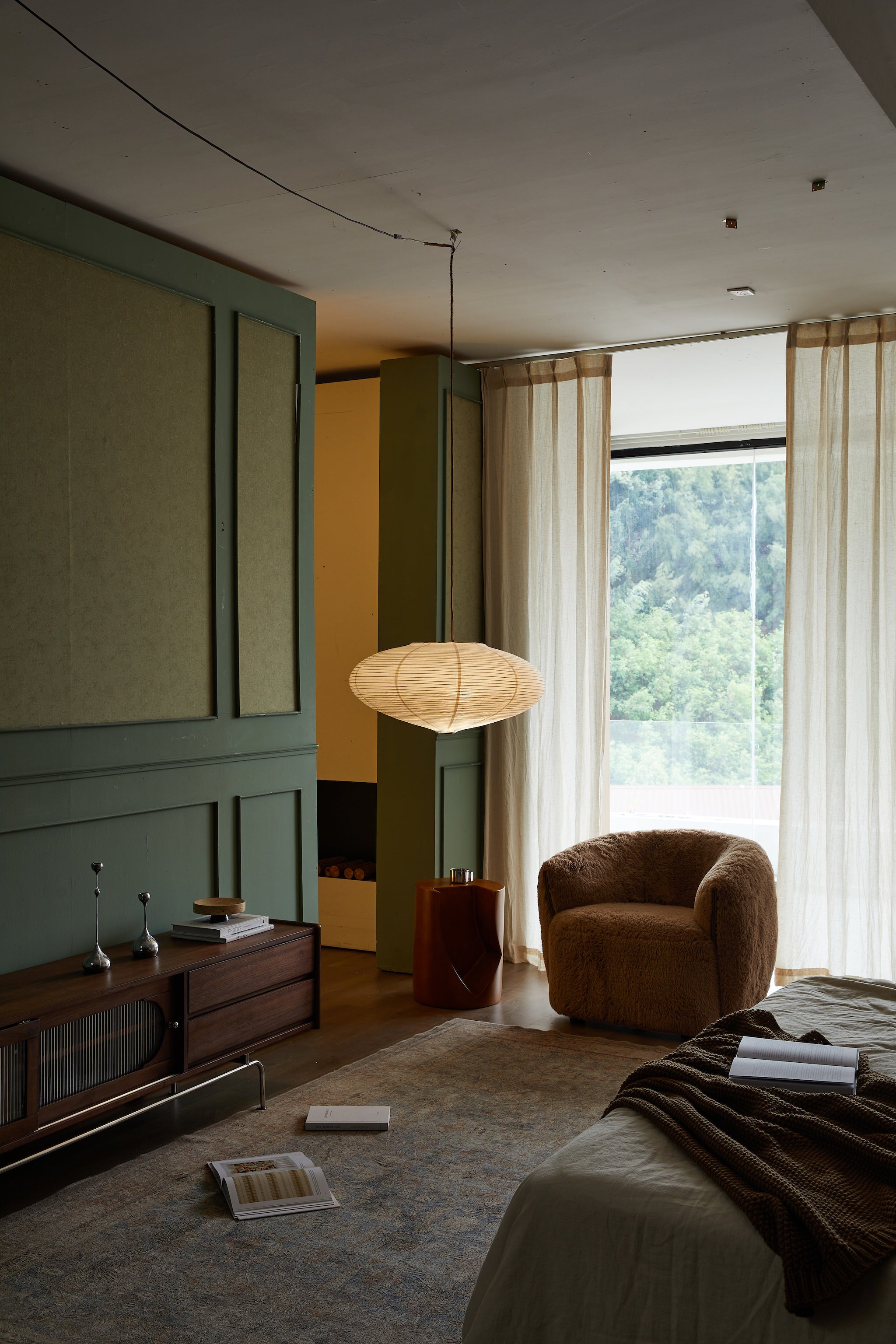 Modern living room with a large window, armchair, and decorative items.