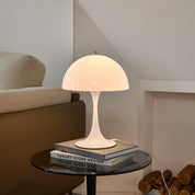 White mushroom table lamp lit on a living room console