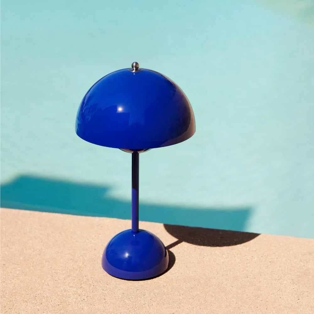 Navy Flowerpot cordless lamp on a table beside a pool